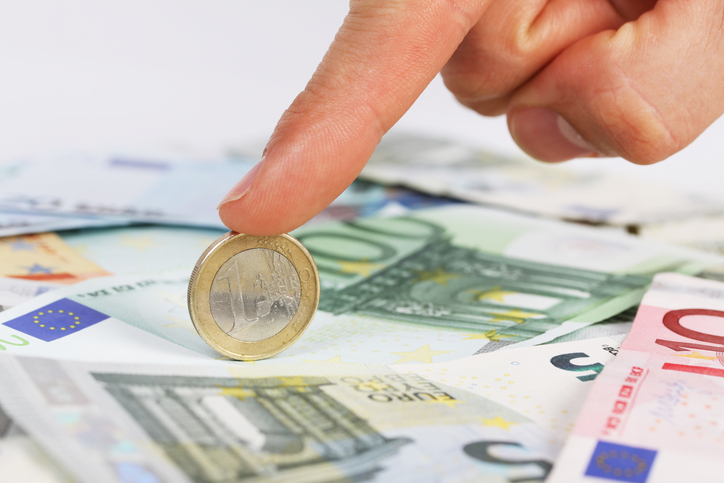 Man's finger holding one euro coin on euro banknotes